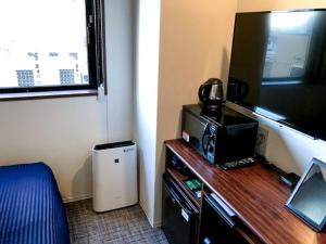 a room with a desk with a television and a table with at HOTEL LiVEMAX Chiba Soga-Ekimae in Chiba