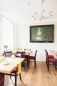 a dining room with tables and chairs and a painting on the wall at Altes Pfarrhaus in Geldern