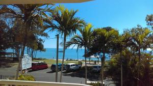 een uitzicht op een parkeerplaats met palmbomen en de oceaan bij Charlton on The Esplanade in Hervey Bay