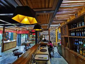 a bar in a restaurant with a woman sitting at the counter at Twelve Manor Xiangdian Yuanyang Rice Terraces Retreat in Yuanyang