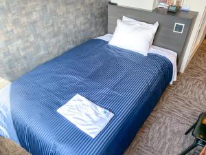 uma cama com um cobertor listrado azul e branco em HOTEL LiVEMAX Shinjuku Kabukicho em Tóquio