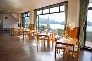 ein Restaurant mit Tischen und Stühlen und einem großen Fenster in der Unterkunft Nojiri Lake Resort in Shinano