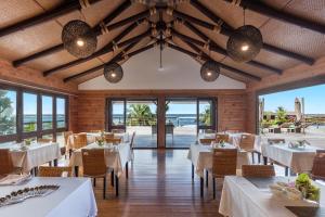 restauracja z białymi stołami i krzesłami oraz widokiem na ocean w obiekcie Aga Reef Resort and Spa w mieście Lalomanu