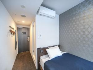 a small bedroom with a blue bed and a wall at HOTEL LiVEMAX Nihonbashi Koamicho in Tokyo