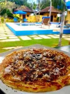 a pizza sitting on a table next to a pool at Secret Garden Bungalows in Nusa Lembongan
