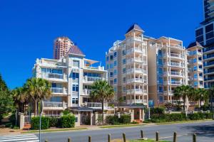 two tall buildings with palm trees in front of a street at La Grande Apartments in Gold Coast