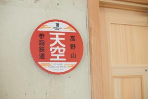 un panneau rouge et blanc sur un mur à côté d'une porte dans l'établissement Nipponia Hotel Koyasan Pilgrimage Railway Operated by KIRINJI - Self Check-In Only, à Kudoyama