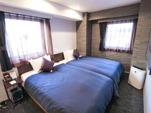 a bedroom with two beds and two windows at HOTEL LiVEMAX Tokyo Kanda-Ekimae in Tokyo