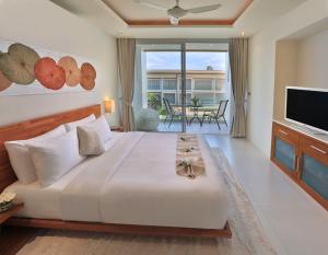 a bedroom with a large white bed and a television at Lanna Samui in Bophut