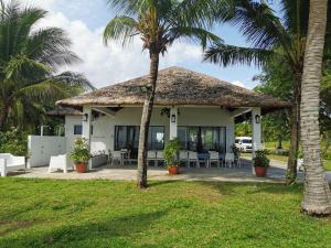 una casa con techo de paja y palmeras en The Resthouse Laiya, en Batangas