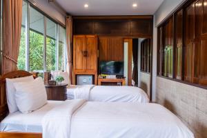 a bedroom with two beds and a television at BaanRimNam Resort Trat in Trat
