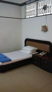 Queen Songkhla Hotel في سونغكلا: غرفة نوم مع سرير وطاولة مع هاتف