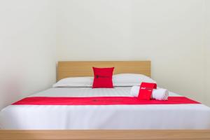 Una cama blanca con almohadas rojas y blancas. en RedDoorz near Universitas Siliwangi Tasikmalaya, en Tasikmalaya