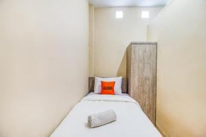 a small bedroom with a bed with an orange pillow at KoolKost near ISI Yogyakarta (with minimum stay applies) in Yogyakarta +6 photos