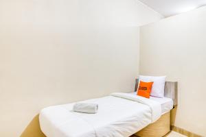 a bedroom with a white bed with an orange pillow at KoolKost near ISI Yogyakarta (with minimum stay applies) in Yogyakarta