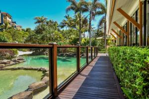 einen Holzsteg, der zu einem Resort mit einem Pool führt in der Unterkunft 1 Bedroom - Private Managed Oaks Resort - Pool and Beach - Alex in Maroochydore