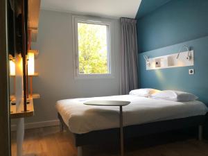 a bedroom with a bed with a table and a window at ibis budget Reims Parc Des Expositions in Reims