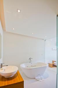 a white bathroom with a tub and a sink at Chi Samui Resort in Bophut