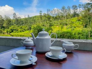 a table with tea pots and cups on a balcony at Heaven Hills Guest House in Maskeliya