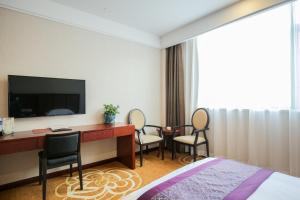 a hotel room with a desk with a television and chairs at Xin Jue Jiayi Hotel Airport and International Resort in Shanghai