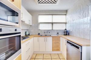 a kitchen with white cabinets and a stove top oven at Bayswaterfront Apartments in Adelaide