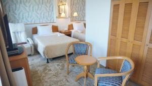 Habitación de hotel con cama, mesa y silla en Naha Beach Side Hotel, en Naha