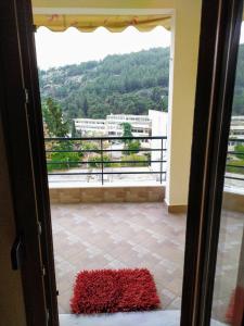 Une porte s'ouvre sur un balcon doté d'un tapis rouge. dans l'établissement Babis apartment, à Kavala