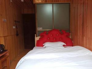 a bed with a large red headboard in a room at Fenghuang Memory Linjiang Inn in Fenghuang County