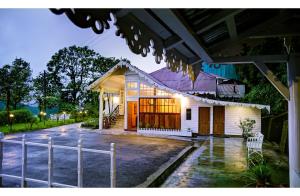 een wit huis met een hek ervoor bij Summit Swiss Heritage Resort & Spa in Darjeeling