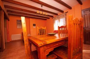 una mesa de comedor de madera en una habitación con paredes de color naranja en Alojamientos Rurales la Fuente en Villalba de la Sierra