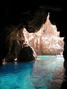 a cave with blue water and a rock formation at I Ginepri B&B in Portoscuso