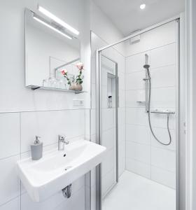 La salle de bains blanche est pourvue d'un lavabo et d'une douche. dans l'établissement Pension Wagener, à Wachtendonk