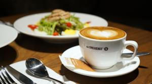 a cup of coffee on a table with a plate of food at Paco Hotel Gangding Metro Guangzhou-Free Shuttle Bus fir Canton Fair in Guangzhou