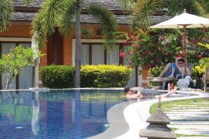 a man and a woman sitting next to a swimming pool at Laguna Villas Boutique Hotel in Ko Yao Noi