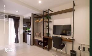 Rovira Suites في دوماغيتي: غرفة معيشة مع مكتب وتلفزيون في غرفة