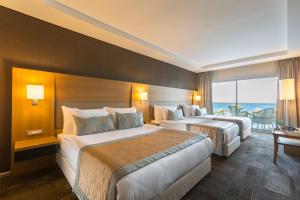 a hotel room with two beds and a large window at Boyalik Beach Hotel & Spa Cesme in Çeşme