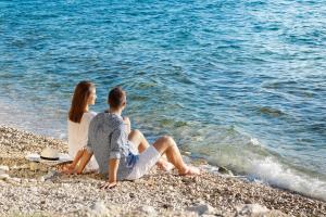 a man and a woman sitting on the beach at Hotel Pinija in Petrcane