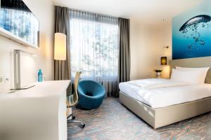 a hotel room with a bed and a blue chair at ACHAT Hotel Bremen City in Bremen