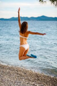 a woman jumping in the air on the beach at Hotel Pinija in Petrcane
