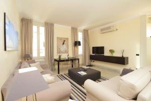 a living room with white furniture and a flat screen tv at Crispi Luxury Apartments - My Extra Home in Rome