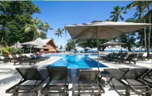 une piscine avec des chaises et un parasol dans l'établissement Berjaya Beau Vallon Bay Resort & Casino, à Beau Vallon