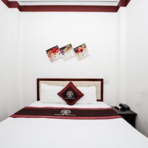 a bedroom with a bed with a white bedspread and avertisement at Brown Bean 2 Hotel in Danang