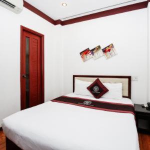 a white bedroom with a white bed and a red door at Brown Bean 2 Hotel in Danang