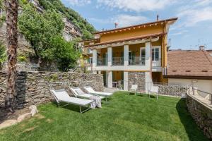 a backyard with white chairs and a stone wall at Camera Molly in Cannero Riviera
