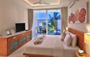 a bedroom with a bed with a television and a balcony at Chi Samui Resort in Bophut
