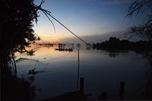 a group of people in boats on a river at sunset at Baan​ Tonlamphu​ Pakpra in Phatthalung