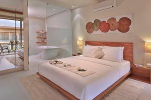a bedroom with a large white bed and a bathroom at Chi Samui Resort in Bophut