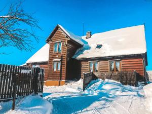 a wooden house covered in snow with a fence at Beskidzki Domek in Kurów