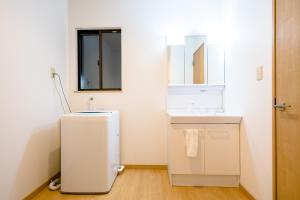 ein kleines weißes Bad mit einem Waschbecken und einem Spiegel in der Unterkunft beautiful Mt.Fuji A in Fujikawaguchiko