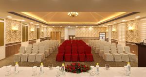 a conference room with red chairs and tables andatoes at Flora Charishma Residency Aluva in Cochin